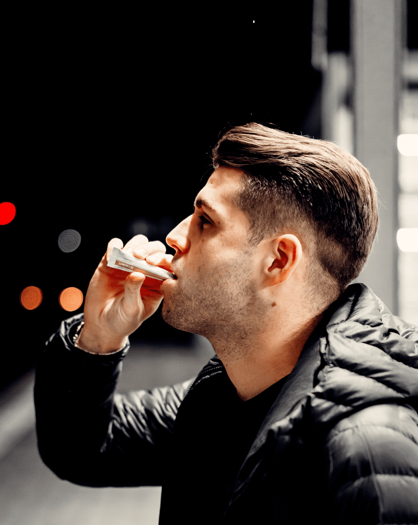 Man taking Cedem Magnesium 400 & B-Complex powder stick at night in an urban setting, showcasing convenient direct use without water for energy and muscle support β Cedem ag